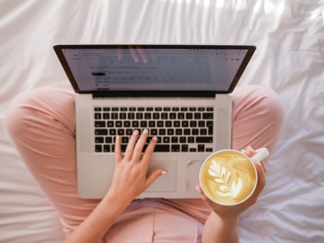 woman on laptop reading with coffee