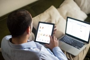 Man using an ipad and laptop to look at a responsive mobile friendly website